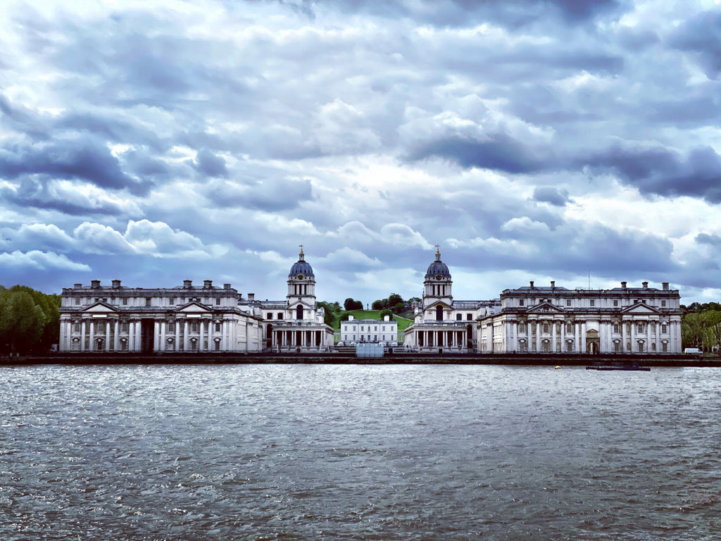 Royal Navy College with river in foreground and cloudy skies overhead